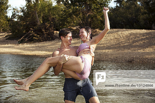 Man lifting girlfriend while standing in lake