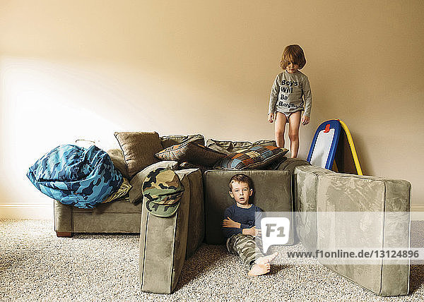 Portrait of boy relaxing while brother standing on sofa