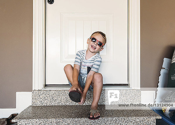 Junge  der Hausschuhe trägt  während er an der Tür sitzt