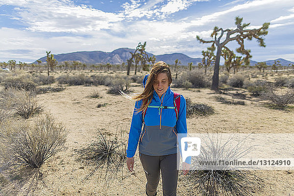 Female hiker with backpack walking on field at Joshua Tree National Park