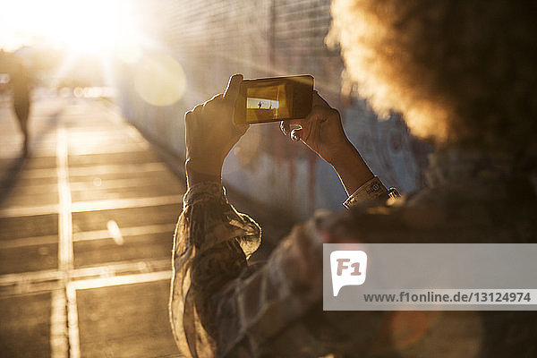 Ausschnitt einer Frau  die an einem sonnigen Tag per Handy fotografiert