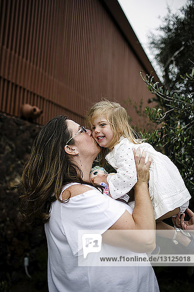 Glückliche Mutter küsst Tochter  während sie am Touristenort steht