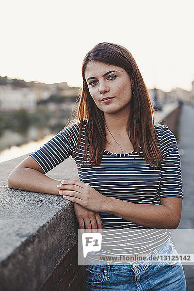Porträt einer selbstbewussten jungen Frau  die an einer Stützmauer in der Stadt steht