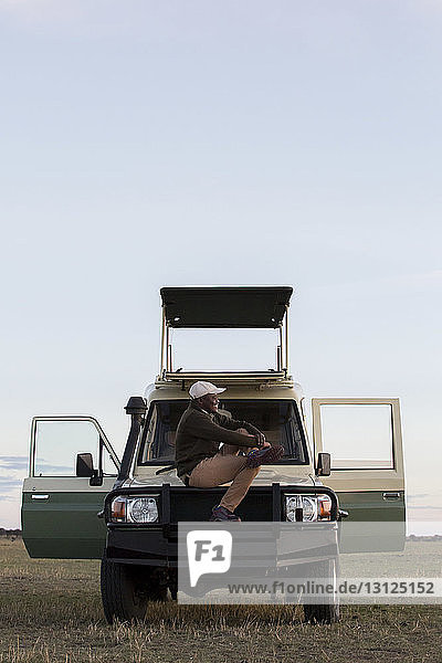 Seitenansicht eines auf einem Fahrzeug sitzenden Mannes im Serengeti-Nationalpark gegen den Himmel