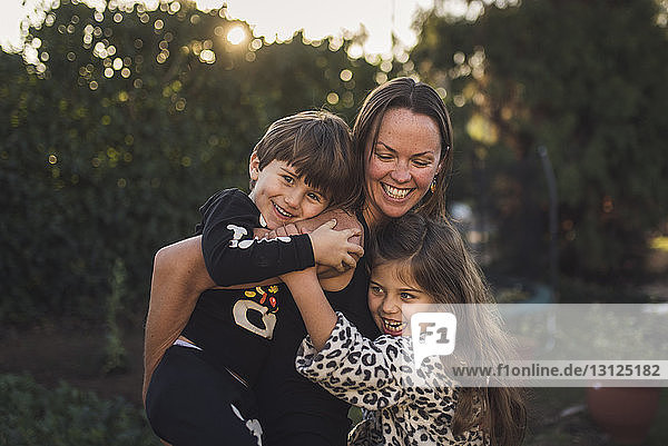Happy mother playing with children in yard during sunset