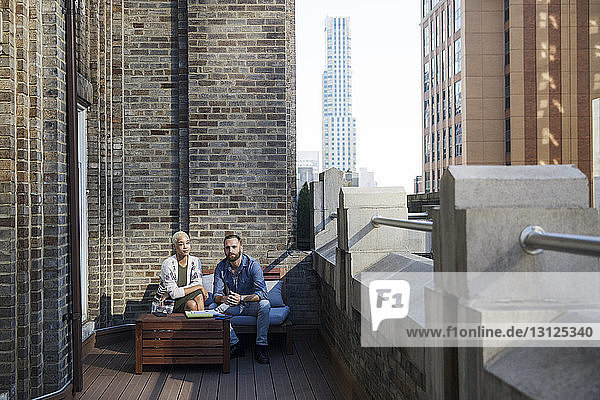 Portrait of colleagues sitting on sofa in office balcony
