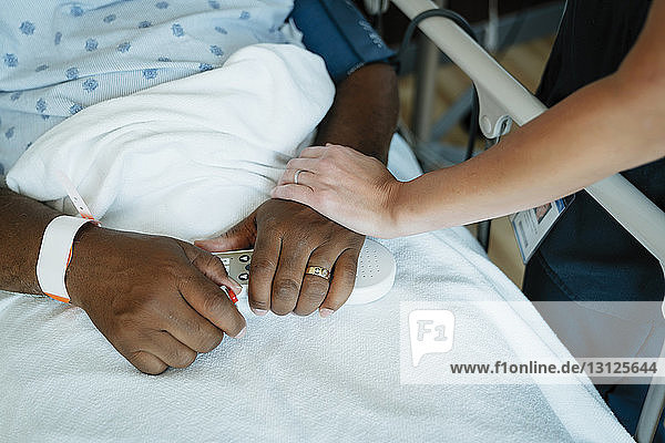 Nahaufnahme einer Krankenschwester  die die Hand eines älteren Patienten auf der Krankenhausstation berührt