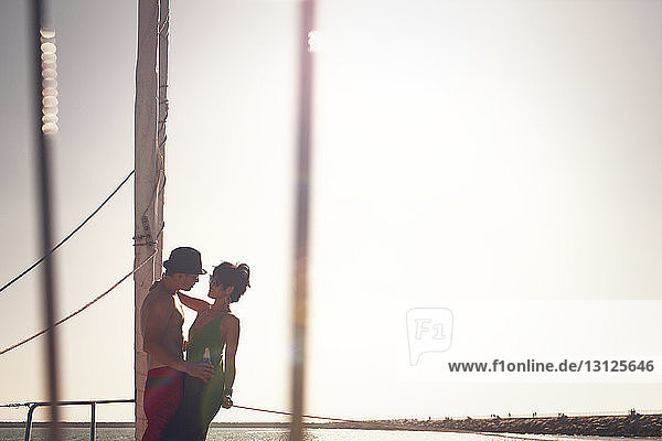 Couple standing on boat against clear sky on sunny day