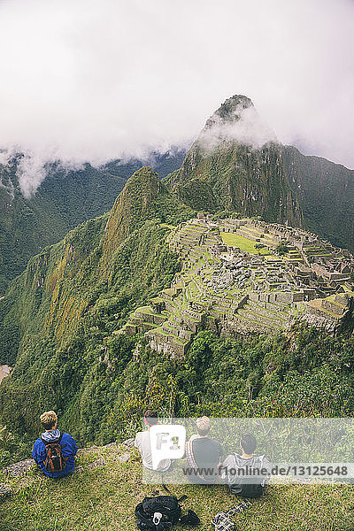 Rückansicht der auf dem Berg sitzenden Freunde gegen Machu Picchu
