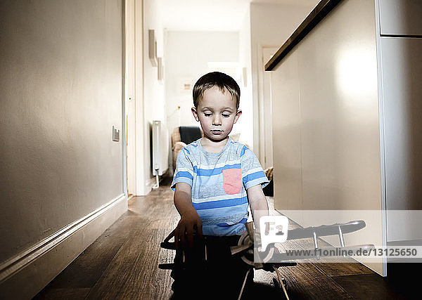 Junge spielt zu Hause kniend mit Modellflugzeug