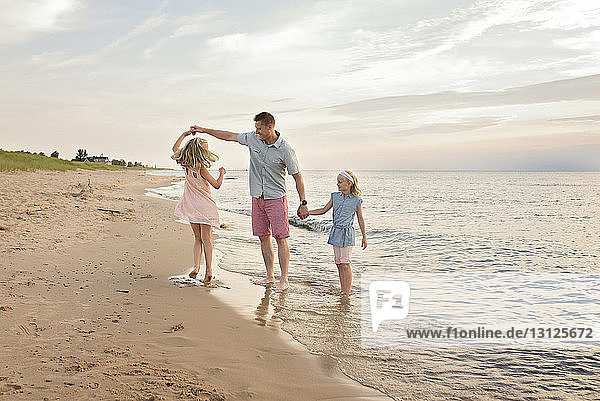 Father playing with daughters on shore at beach