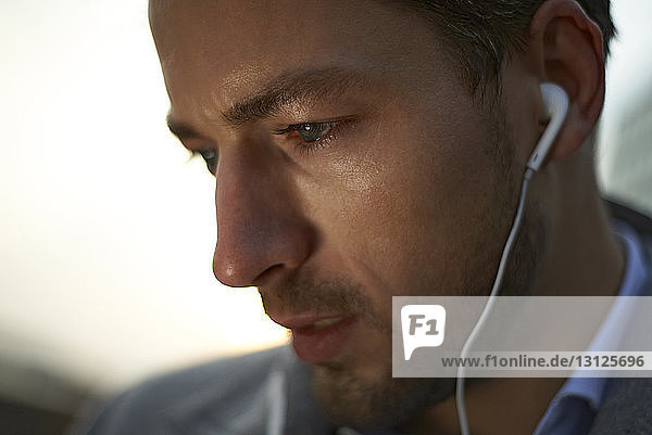 Close-up of businessman listening music while standing outdoors