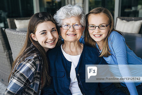 Porträt der glücklichen Großmutter und Enkelinnen auf der Veranda sitzend