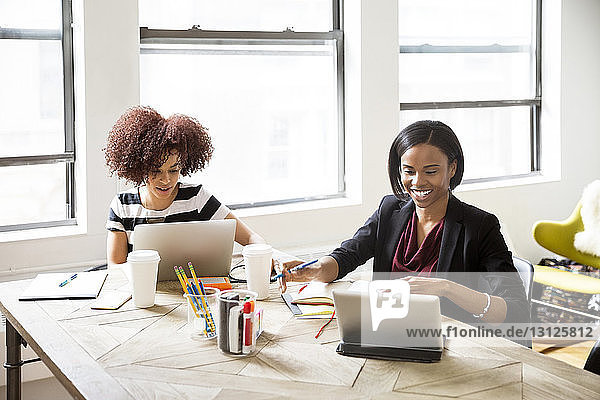 Geschäftsfrauen mit Laptop und Tablet-Computer am Schreibtisch im Kreativbüro