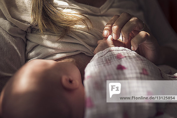 Midsection of mother breastfeeding newborn daughter at home
