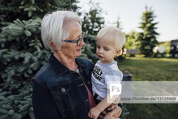 Großmutter trägt Enkel  während sie auf dem Bauernhof steht