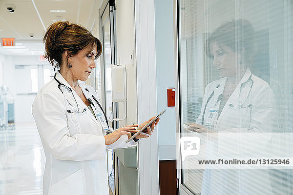 Seitenansicht einer Ärztin am Tablet-Computer in der Krankenhauslobby