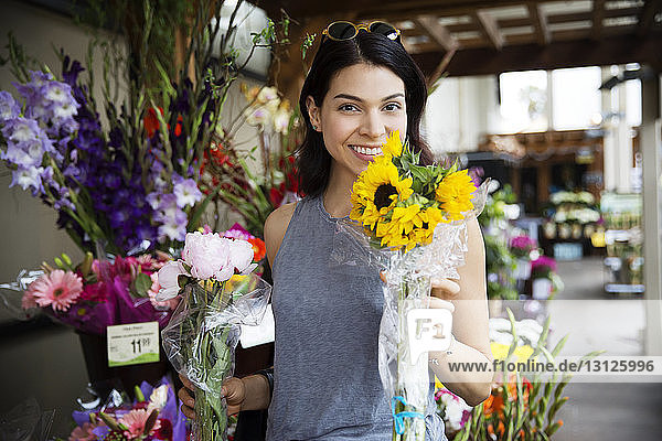 Porträt einer lächelnden  an Sonnenblumen riechenden Frau im Blumenladen