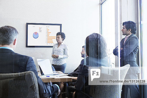 Businesswoman giving presentation to colleagues in conference room