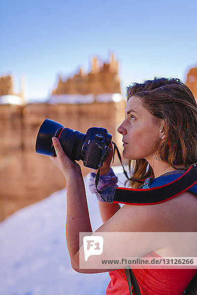 Hiker photographing while standing on mountain at Bryce Canyon National Park