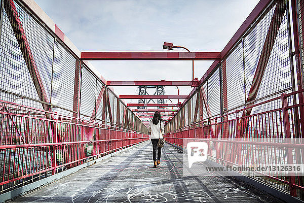 Rückansicht einer jungen Frau  die über die Williamsburg Bridge geht