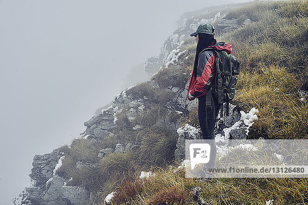 Seitenansicht einer Wanderin  die bei nebligem Wetter auf den Balkangebirgen steht