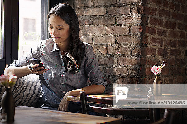 Woman using smart phone while sitting in cafe