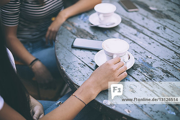 Mitsektion von Freunden mit Kaffee auf dem Tisch sitzend im Straßencafé