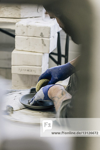 Close-up of craftsman using pottery wheel while working in art studio