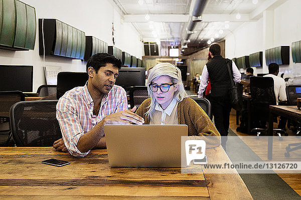 Geschäftsleute  die während der Arbeit am Laptop im Kreativbüro diskutieren