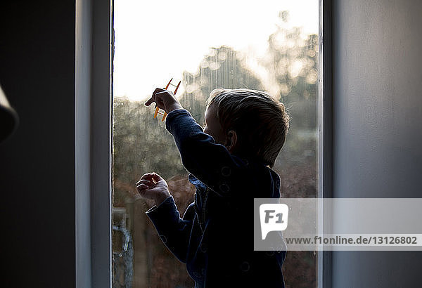 Junge spielt mit Spielzeug  während er zu Hause am Fenster sitzt