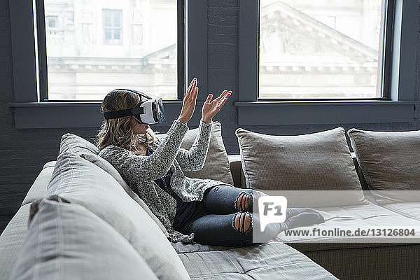 Geschäftsfrau trägt Virtual-Reality-Simulator und klatscht im Büro