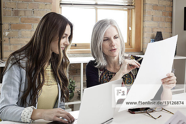Mature female manager explaining plan to executive in creative office