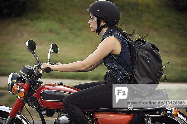 Seitenansicht einer Motorrad fahrenden Frau auf der Straße