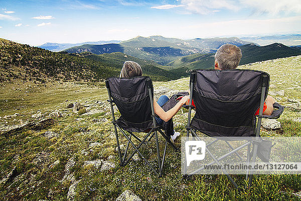 Rear view of couple sitting on chair against mountain