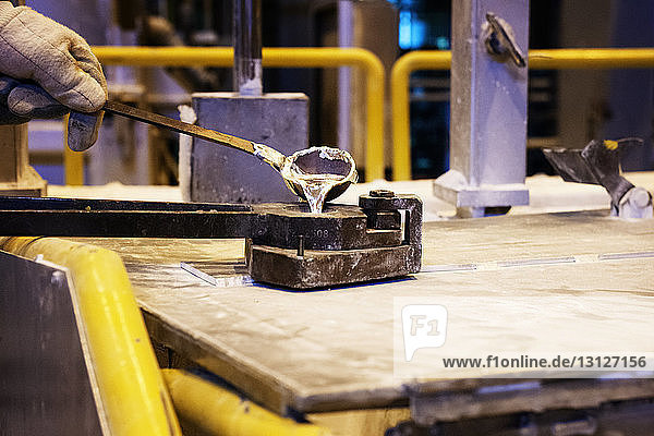 Ausgeschnittenes Bild eines Arbeiters  der Flüssigkeit in der Metallindustrie gießt