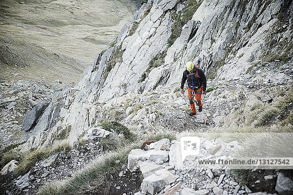 Hochwinkelaufnahme eines Wanderers  der beim Bergsteigen auf Felsen geht