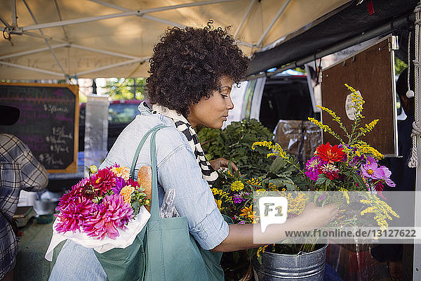 Frau wählt Blumen aus Container auf dem Markt aus
