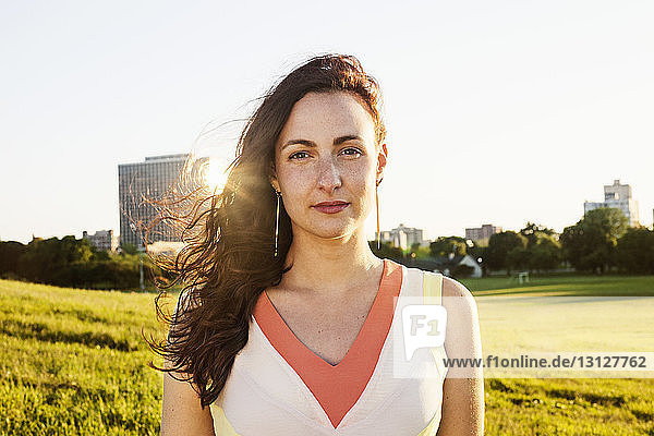Porträt einer jungen Frau auf Grasfeld vor klarem Himmel