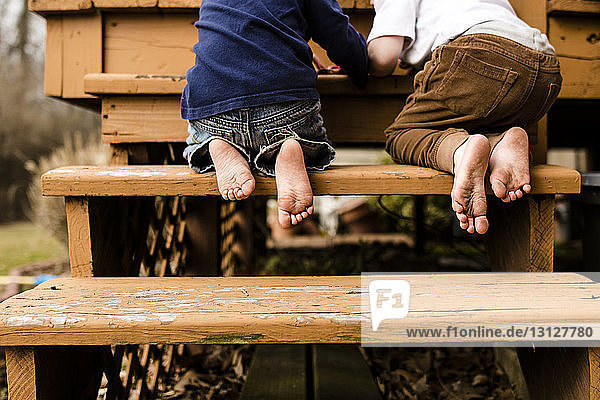 Niedrige Sektion von Brüdern die auf Stufen auf dem Spielplatz kniend spielen