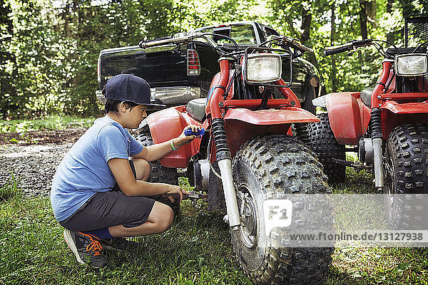 Junge repariert ATV auf Rasenplatz
