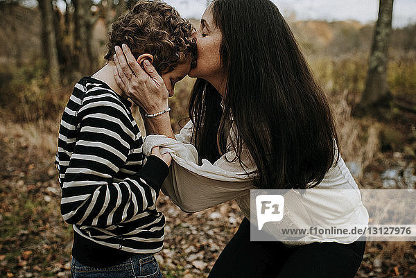 Side view of mother kissing on son's head at park