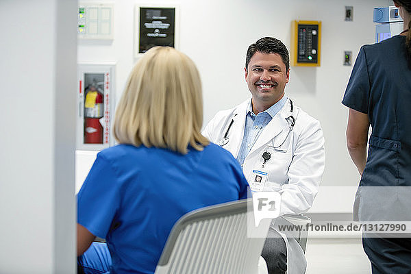 Happy doctor looking away while female colleagues in foreground