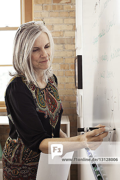 Reife Geschäftsfrau schreibt im Kreativbüro auf Whiteboard