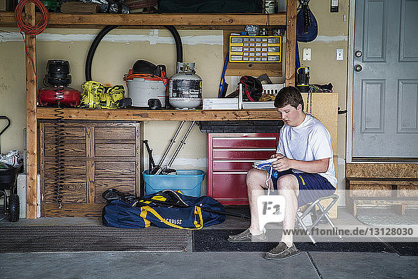 Junge hält Netzgewebe  während er zu Hause auf einem Hocker sitzt