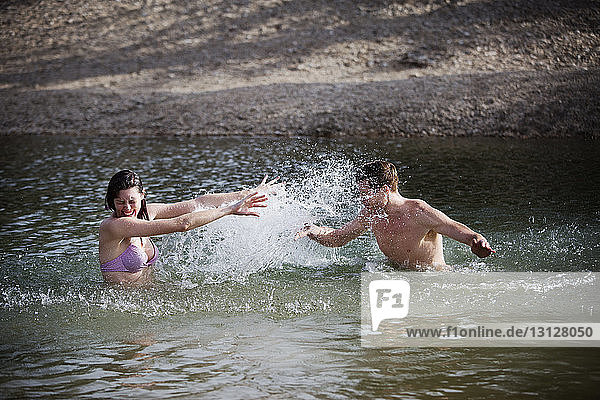 Couple splashing water while enjoying in lake