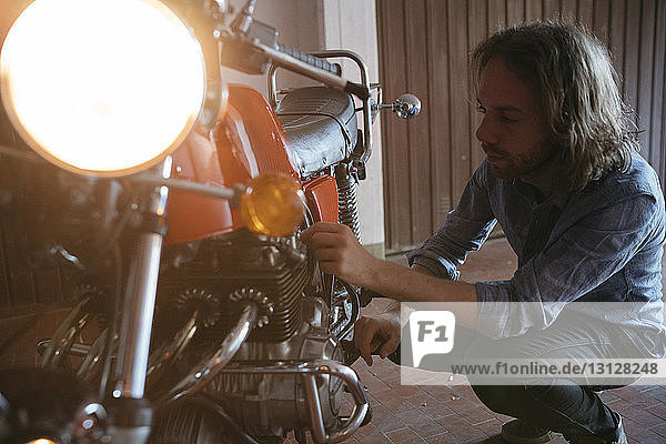 Mann repariert Motorrad in Werkstatt