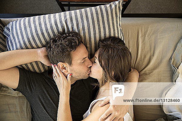 Hochwinkelansicht eines Paares  das sich küsst  während es auf dem Bett liegt