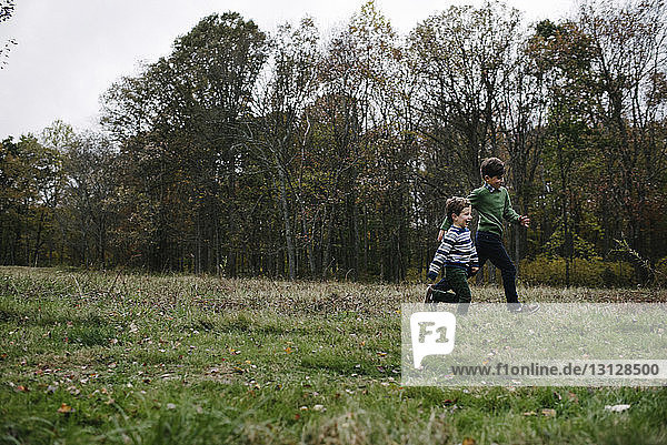 Brothers running on grassy field at park