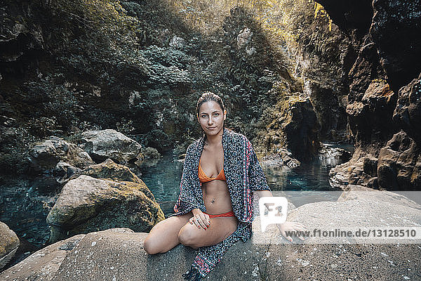 Bildnis einer Frau im Bikini mit Schal auf einem Felsen sitzend